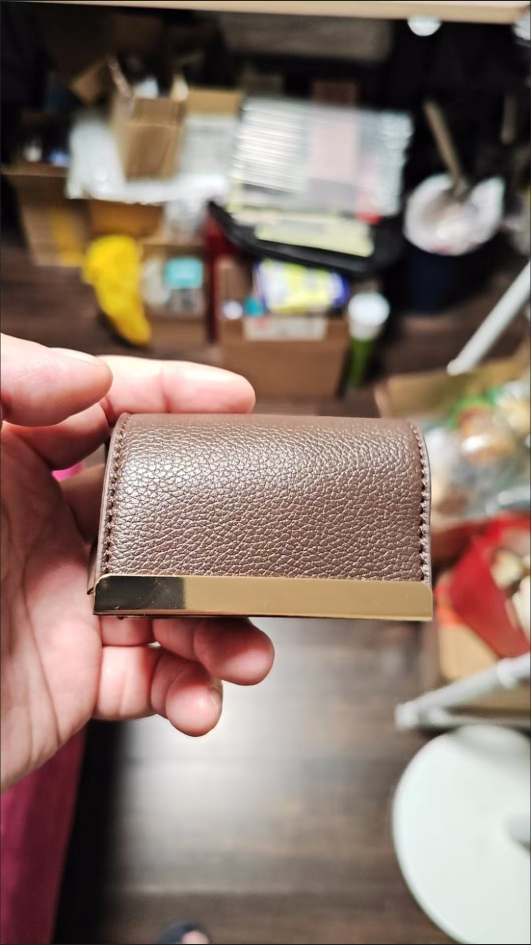 Brown folded bag charm held in hand
